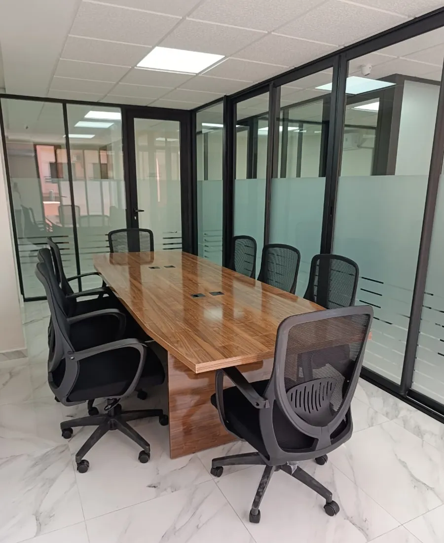 Salle de réunion vitrée avec grande table et huit fauteuils